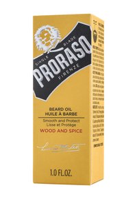 Proraso skäggolja har en förpackning i en gul låda med svarta accenter, som anger "Trä och Kryddor." Den innehåller en lejonsymbol och har en texturerad yta.