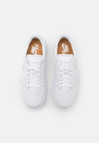 Baskets blanches avec une tige en cuir lisse, une boîte à orteils perforée et des lacets plats. Comprend des semelles intérieures en liège avec un logo imprimé.