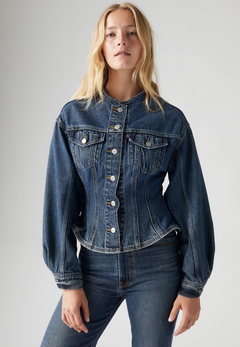 Veste en jean bleue avec une taille ajustée, fermeture à boutons, deux poches poitrine et manches longues. Présente des détails de couture subtils et un ourlet arrondi.