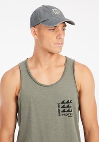 Olijf groene tanktop met een ronde halslijn en een grafisch ontwerp aan de voorkant met golven en tekst. Grijze baseballpet met geborduurd logo.