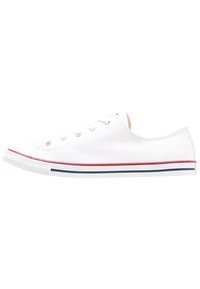 Baskets en toile blanches avec un design à profil bas, bout rond et accents rouges et navy sur la semelle en caoutchouc, présentant cinq œillets.