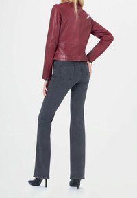 Punainen nahkatakki, joka on yhdistetty harmaisiin leveälahkeisiin farkkuihin. Takissa on vartalonmyötäinen muotoilu vetoketjuineen, ja farkuissa on klassinen viiden taskun tyyli.