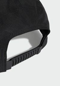 Gorra de béisbol de tela negra con correa ajustable de plástico negro tipo snapback y detalles de costura sobre fondo claro.