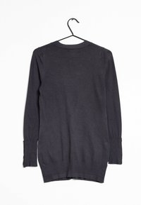 Pull noir à manches longues, en tissu doux, avec un col rond, des fentes latérales et des détails de boutons sur le poignet. Accroché sur un crochet noir.