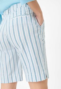 Shorts rayés avec des rayures verticales bleues et blanches, dotés d'une poche arrière et d'une poche latérale, fabriqués dans un tissu léger.