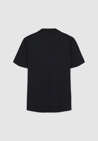 Polo noir à manches courtes vu de dos avec un col classique sur un fond gris clair uni.