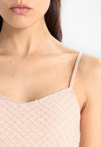 Světle růžový, texturovaný top na ramínka s diamantovým vzorem, tenkými nastavitelnými šňůrkami a detailním scalloped výstřihem.