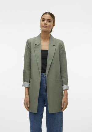 Blazer verde claro con un corte entallado, solapas de muesca y dos bolsillos laterales. Presenta mangas enrolladas con una tela clara contrastante.