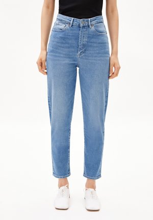 Jeans in denim azzurro chiaro con vita alta, vestibilità dritta, cinque tasche e una texture liscia. Abbinati a scarpe bianche con lacci.
