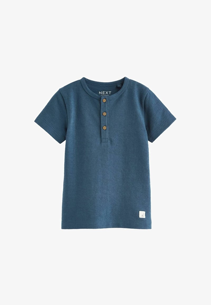 Donkerblauwe T-shirt met korte mouwen, gemaakt van textuurstof. Heeft een ronde halslijn en drie bruine knopen aan de voorkant. Klein wit logo aan de zoom.
