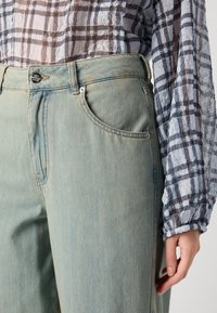 Lyseblå denimjeans med avslappet passform, med et klassisk femlommers design, subtil søm og metallknappelukking.