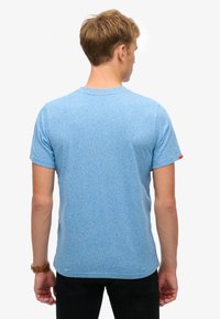 Jasnoniebieski t-shirt z krótkim rękawem, wykonany z melanżowej tkaniny. Posiada okrągły dekolt i mały czerwony akcent na rękawie. Standardowy krój.