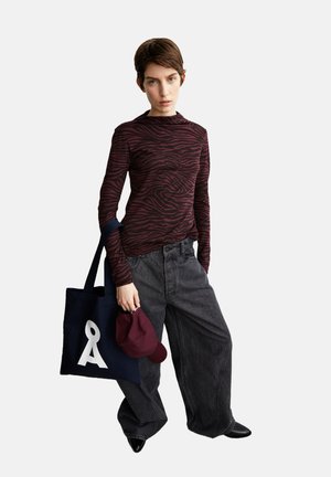 Bordeauxrot gestreiftes Langarmshirt, weit geschnittene dunkelgraue Jeans, marineblaue Tote-Tasche mit weißem Logo, bordeauxrotes Cap, schwarze spitze Schuhe.