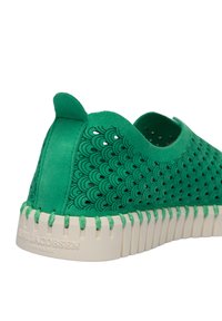 Scarpa verde slip-on con un motivo testurizzato e fori di ventilazione. La suola è bianca con un design a righe e branding in rilievo.
