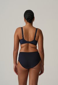 Nawiebieski stanik i majtki o wysokim stanie. Miękka tkanina z regulowanymi ramiączkami. Bezszwowy krój z delikatnymi falbaniastymi krawędziami na pasie.