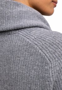 Maglione a maglia grigia chiara con cappuccio ampio e ripiegato, tessuto testurizzato con coste e design aderente e strutturato.