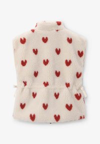 Gilet en polaire avec un col haut, de couleur crème recouvert de motifs en forme de cœur rouges, présentant une taille cintrée et des liens sur le côté.