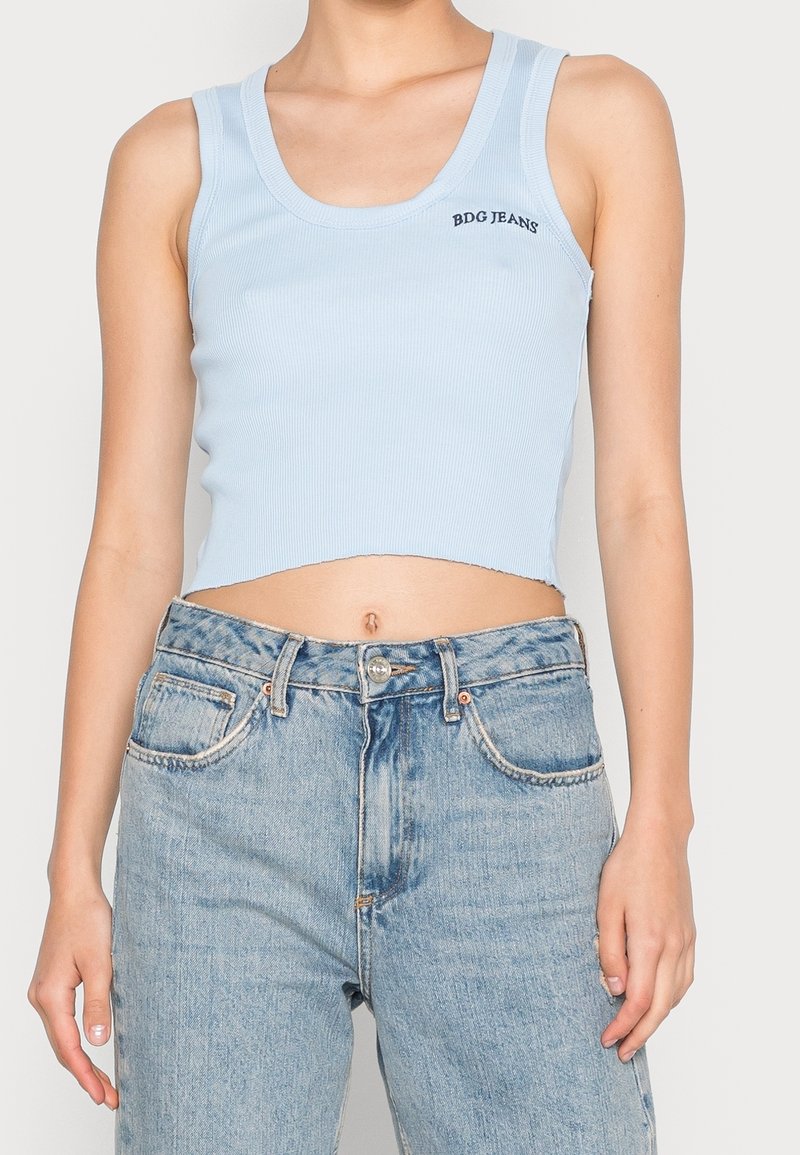 Světle modrý žebrovaný krátký top s kulatým výstřihem a nápisem "BDG JEANS". Kombinace s vysokým pasem a bledými modrými džíny.