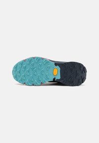 Vibram sål med et blandet farvedesign; turkis gummi med hexagonale pigge for greb og holdbarhed, mørkeblå sektioner for struktur.
