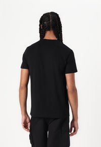Black short-sleeve t-shirt with a crew neckline, made of smooth cotton fabric, seen from the back, featuring a relaxed fit.