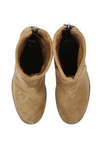 Bottines en daim marron avec un design plié, bout rond et fermeture zippée latérale. La texture est douce avec une semelle en caoutchouc plate.