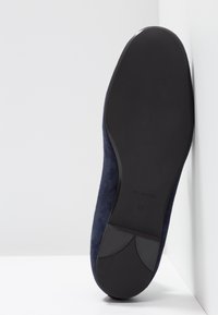 Semelle d'une chaussure en daim bleu foncé indiquant la taille 37 et « Made in Spain » embossé sur la semelle noire lisse.