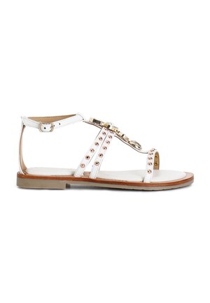 Valkoiset litteät sandaalit, joissa on ohut nauhadesign, kultaiset yksityiskohdat ja koristeelliset rose gold -niitit sivuilla. Sileä pohja, jossa on vaaleanruskeita yksityiskohtia.