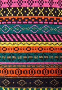 Tissu tricoté coloré avec des rayures horizontales alternées comportant des motifs géométriques et floraux en rose, noir, jaune, orange et vert.