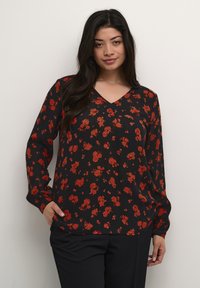 Sort blomstrede bluse med V-hals, lange ærmer og løs pasform, prydet med røde og orange blomster mønstre på et let stof.