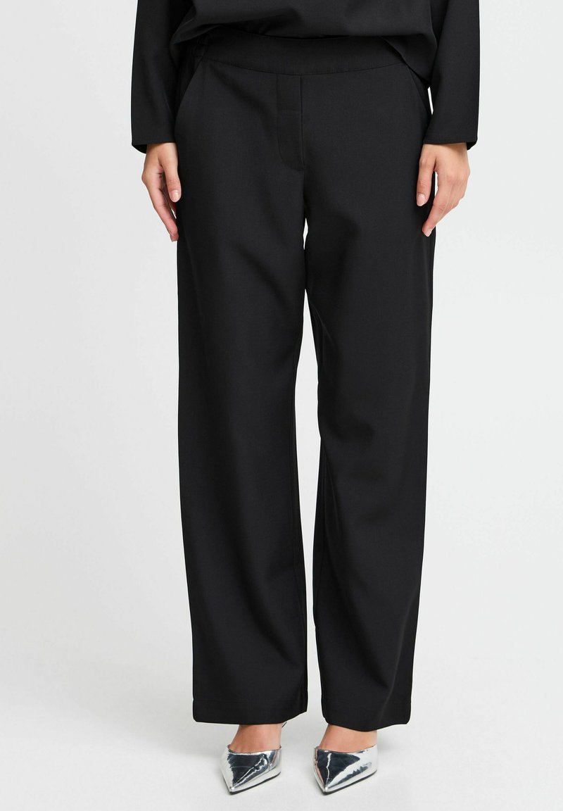 Schwarze weit geschnittene Hose mit glatter Textur, maßgeschneidertem Design, elastischem Bund und ohne sichtbare Taschen.