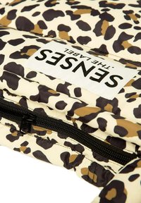 Leopard print padded fabric with beige, brown, and black spots. Features a black zipper and a white tag with "SENSES" in black text.