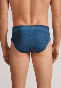 Dunkelblaue Herrenunterwäsche mit glatter Textur, elastischem Bund und minimalistischem Design. Die Rückansicht zeigt die körpernahe Form und klare Linien.