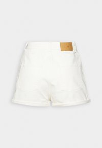 Shorts de mezclilla blanca con dobladillo enrollado, dos bolsillos traseros y una etiqueta de marca de cuero marrón en la cinturilla.