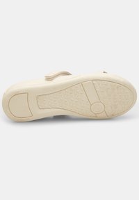 Beige Schuhe mit einer strukturierten Gummisohle, ausgestattet mit einem Klettverschluss und verstärkten Kanten für Langlebigkeit. Flaches und funktionales Design.