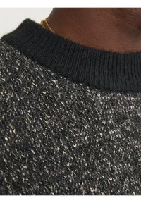 Maglione lavorato a maglia con un colletto nero, corpo grigio testurizzato con spruzzi di crema, che mette in mostra un design accogliente e dettagli di cucitura visibili.