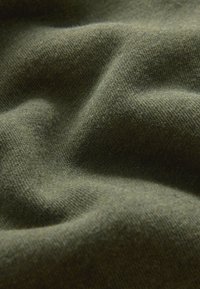 Olivgrüner Stoff mit einer weichen, strukturierten Oberfläche, die sanfte Falten und ein gestricktes Muster zeigt. Geeignet für Bekleidung oder textile Anwendungen.