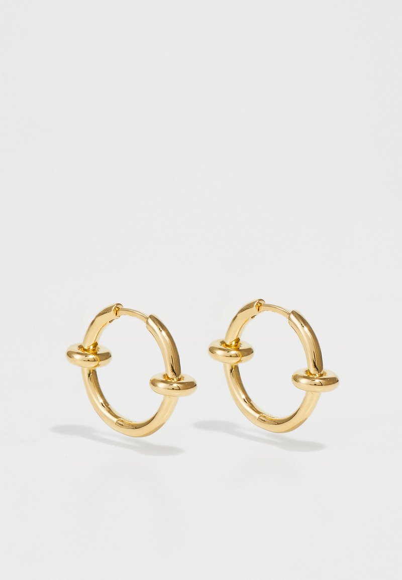 Kuldse õhukesed rõngas kõrvarõngad on siledad ja ümarad, keskel on kaks aktsenti, läikiv viimistlus ja kindel klamber mugavaks kandmiseks.