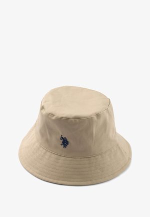 Bézs színű, szövetből készült vödörkalap, puhára kialakított tetejével és széles karimájával, sötétkék logóval hímezve az oldalán.