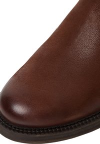 Bruna läderankelboots med en slät yta, rund tå, texturerad yta och en gummisula med sömdetaljer.