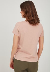 Camiseta de manga corta color rosa claro con cuello redondo, hecha de algodón suave, con una textura lisa y un ajuste relajado.