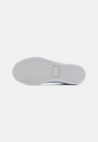 Bijela potplat tenisice s herringbone uzorkom, s Lacoste logom. Glatka tekstura, zaobljen oblik i izdržljiv gumeni materijal.