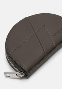Grauer Lederkartenhalter in runder Form, mit sichtbaren Nähten und einem silbernen Reißverschluss. Mit geprägtem Logo auf der Oberfläche.