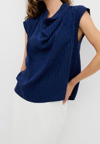 Top senza maniche color blu navy con scollatura drappeggiata e sottile motivo a strisce zebrate, realizzato in tessuto leggero, con una vestibilità rilassata.