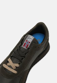 Sneaker grigie scure con una combinazione di materiali suede e mesh. Presentano lacci beige, una fodera interna blu e un'etichetta con un design rosso, bianco e blu.