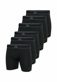 Six shorts de compression noirs pour le sport avec des ceintures grises, logos Adidas à l'avant, disposés en ligne diagonale sur un fond blanc.