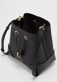 Bolsa de mano negra hecha de cuero texturizado, con herrajes dorados, correa de hombro ajustable y cierre de cordón. Logo visible en la parte frontal.