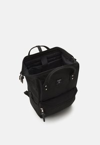 Czarna plecak wykonany z trwałego materiału, z dużą główną komorą, górną rączką i przednią kieszenią na zamek, z regulowanymi szelkami.