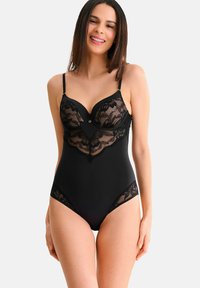 Zwarte body met doorschijnende kanten panelen, verstelbare bandjes, gevormde cups en een decoratieve knoopaccent in het midden.