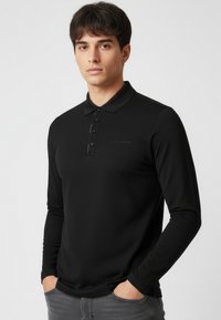 Czarna koszulka polo z długim rękawem, z kołnierzykiem zapinanym na guziki, gładką fakturą i subtelnym logo na przodzie.