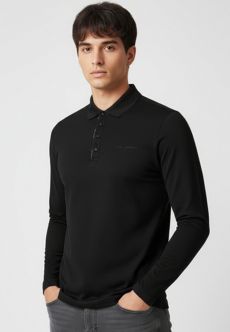 Czarna koszulka polo z długim rękawem, z kołnierzykiem zapinanym na guziki, gładką fakturą i subtelnym logo na przodzie.